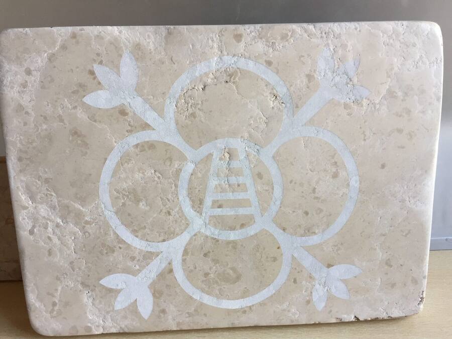 Logo con un'ape stilizzata inciso su una lastra di travertino