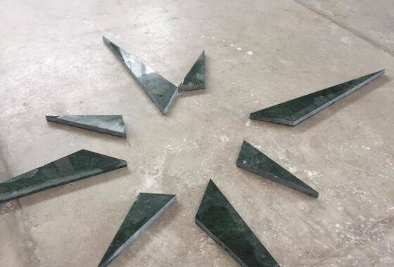Dettaglio di un intarsio geometrico in marmo verde su fondo chiaro
