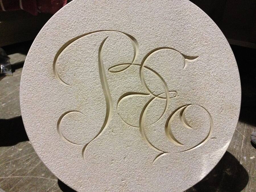 Monogramma inciso su un tondo di pietra chiara
